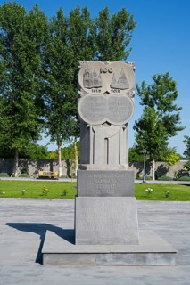 Stone monument with inscription in front of tall trees, in the garden of the Yazidi temple, Yazidi