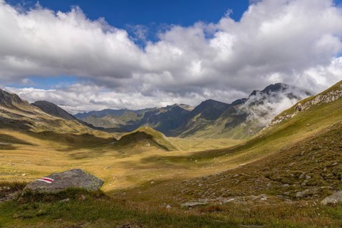 View from Passo del Sole in Alpe Carorescio with Piano Grande plateau and hiking trail marker,