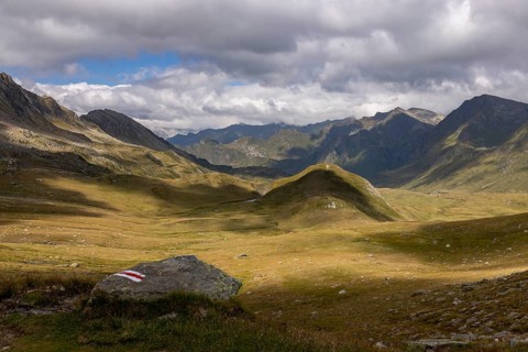 View from Passo del Sole in Alpe Carorescio with Piano Grande plateau and hiking trail marker,