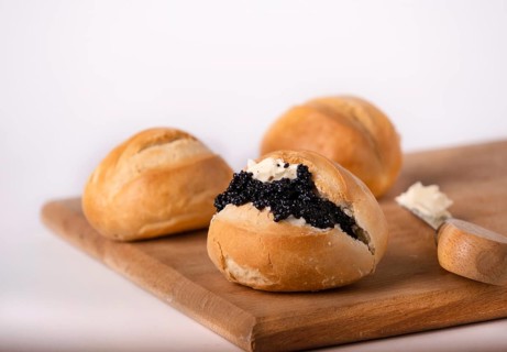 Round wheat buns with butter and black caviar, copy space