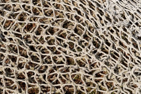 Fishing net lying on the ground, textured background