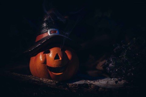 Pumpkin lantern with witch's hat in a spooky, dark setting