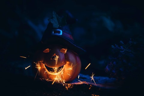 Glowing pumpkin with hat and sparks in a dark, mystical atmosphere, Halloween