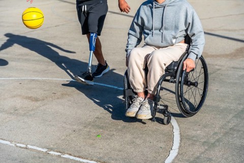 Two people with different physical disabilities staying active on an outdoor basketball court, one