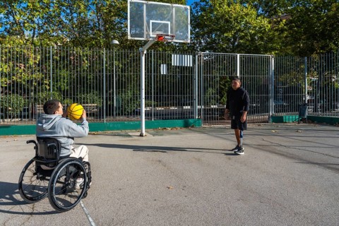 Two young men with disabilities, one using a wheelchair and the other a prosthetic leg, enjoying a