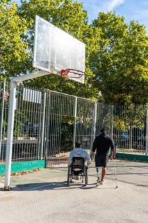 Disabled men on an outdoor basketball court, one in a wheelchair and another with a prosthetic leg