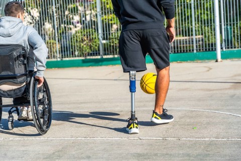 Young men with disabilities enjoying a basketball game together on an outdoor court, embracing