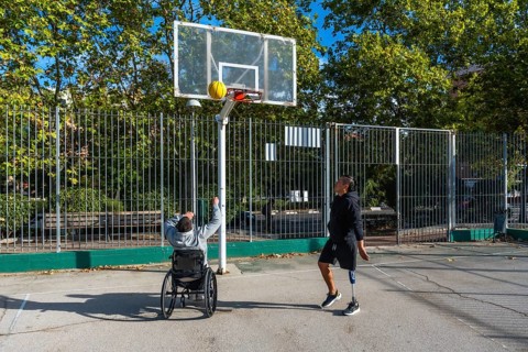 Men with prosthetic leg and wheelchair playing basketball outdoors, demonstrating inclusion,