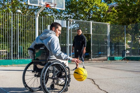 Two men experiencing disabilities, one in a wheelchair and another with a prosthetic leg, are