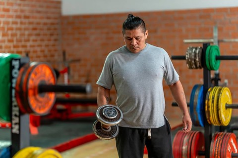 Mature man concentrating on a bicep curl with a dumbbell in a gym, focused on strength training,