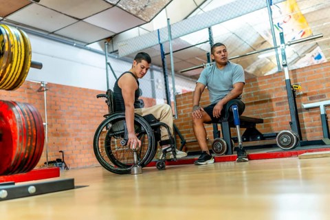 Adaptive athletes with physical disabilities engaging in training at a gym, one man in a wheelchair