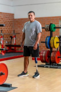 Male amputee athlete standing confidently in a gym, showcasing his prosthetic leg and symbolizing