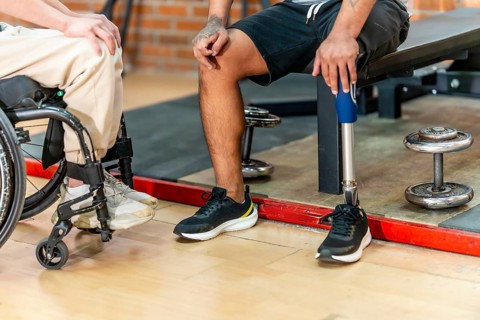 Disabled men, one in a wheelchair and another with a prosthetic leg, sharing a moment of