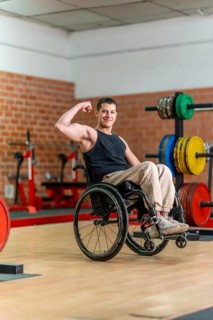 Young man in a wheelchair posing with a flexed bicep, showing determination and strength while