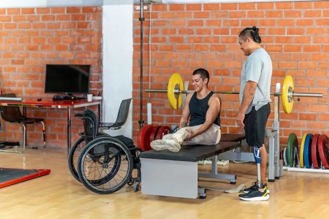 Two adaptive athletesone with a prosthetic leg and one using a wheelchairsupport each other during