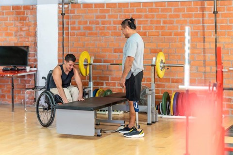 Adapted athletes focusing on their fitness routine at a gym, with one man using a wheelchair and