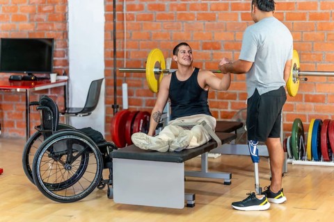 Two men with disabilities celebrate progress in a modern gym, fist bumping after a workout one