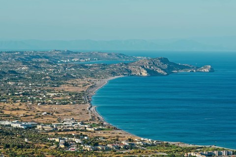 Wide coastline of Kolymbia with sandy beach and blue sea under a clear sky, Church of the Virgin