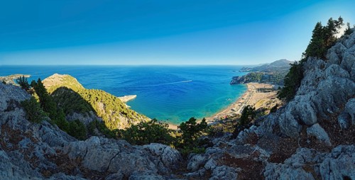 Panoramic view from the cliffs at Kyra Psili church to the sandy beach of Tsambika with deep blue