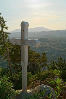 A wooden cross on a hill with a view of mountains and wooded landscape, Church of the Virgin Mary