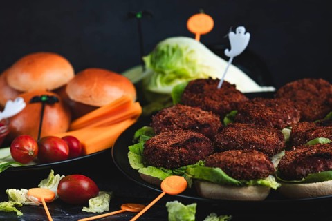 Burger buns with patties, salad, ingredients and Halloween decoration