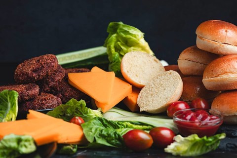 Meatballs and cheese on a bed of lettuce with burger buns and fresh vegetables