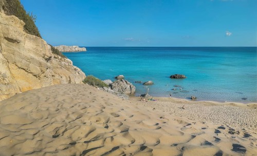 Tsambika beach with fine sand and large rocks on a sunny day, azure blue water and clear sky,