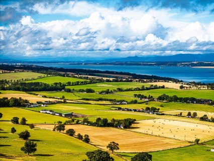 Fields and farms over Scotish farms and Forth Estuary from drone, House of the Binns, Binns Tower,
