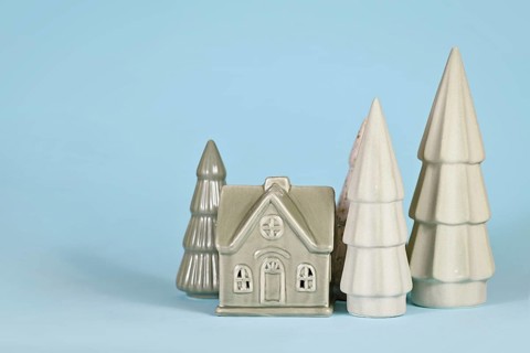 Light green ceramic Christmas trees and house on blue background
