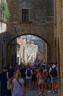 A busy historic alleyway with people walking through an alley under a stone arch, Knights Street,