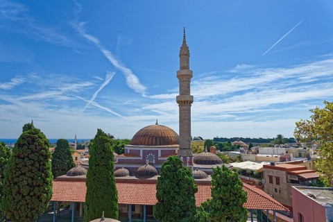 A minaret and domes in a tranquil cityscape with cypress trees and blue sky, Suleiman Mosque,