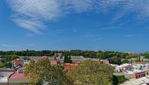 View of a historic old town with many trees and traditional buildings under a clear blue sky,
