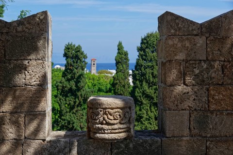 View from a stone wall with battlements of green trees and the distant sea under a blue sky, Grand