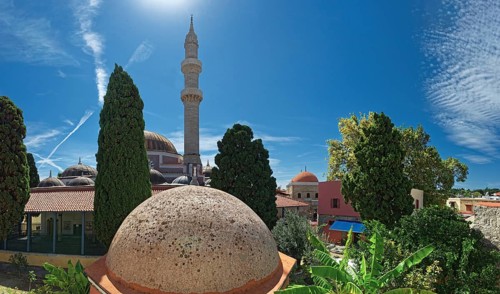 A minaret with domes and trees against a bright blue sky in a summer atmosphere, Suleiman Mosque,