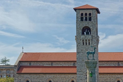A church Ekklisia Evaggelismos with red roof and bell tower, in the foreground the deer cow statue
