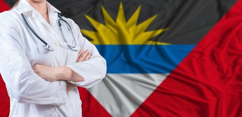 Doctor with crossed arms on Antigua and Barbuda flag. Antigua and Barbuda health and care concept.