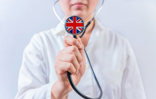 Female doctor holding stethoscope with United Kingdom flag. National health system of United