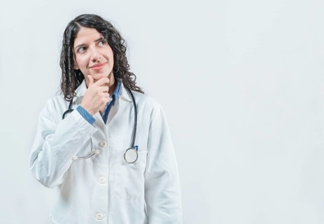 Young female doctor thinking with her hand on her chin, isolated. Thoughtful young female doctor