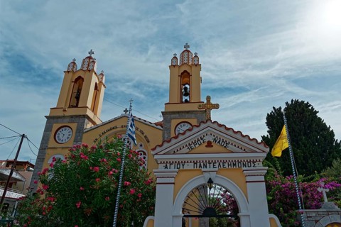 Yellow church with decorative entrance gate and bell towers against the sky, Greek Orthodox Church