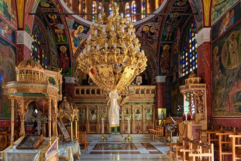 Richly decorated interior of an Orthodox church with icons and stained glass windows, Greek
