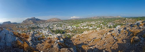 Panoramic view of the town of Archangelos in the middle of a vast and sunny mountain landscape,