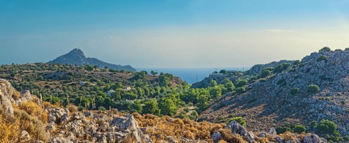 Hilly landscape near Stegna with green vegetation, sea view and blue sky, Stegna, Archangelos,
