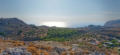View over a barren range of hills near Stegna to the sea under the morning sun, Stegna,