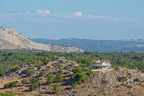 Single house on a rocky hill in the middle of a barren and lush landscape, Archangelos, Rhodes