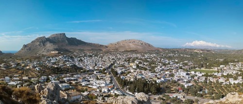 Panorama of the town of Archangelos in a sunny landscape, surrounded by mountains under a clear