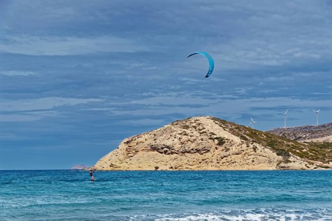Prasonisi beach with a view of the sea and rocky island with visible kite and wind turbines. Windy