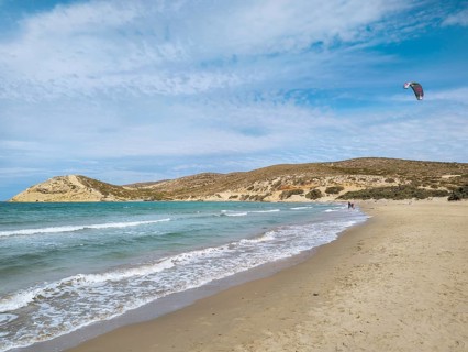 Quiet beach of Prasonisi with gentle waves and a kite in the sky under a slightly cloudy sky,