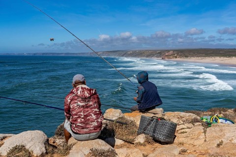 Anglers on the cliffs at the viewpoint above Praia da Bordeira beach, near Carrapateira, popular