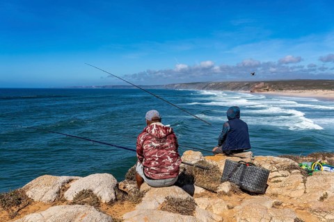 Anglers on the cliffs at the viewpoint above Praia da Bordeira beach, near Carrapateira, popular