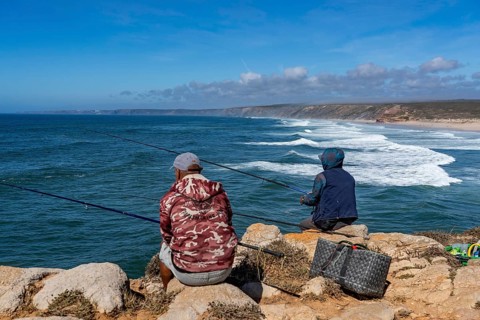 Anglers on the cliffs at the viewpoint above Praia da Bordeira beach, near Carrapateira, popular